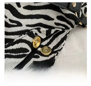 Detailed macro view of the strong gold magnetic clasp on a zebra pattern canvas bag