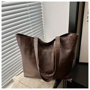 Close-up of brown PU leather tote bag with grainy texture on soft knit fabric