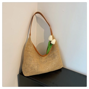 Detail of woven straw tote bag featuring brown PU leather strap and textured hobo design