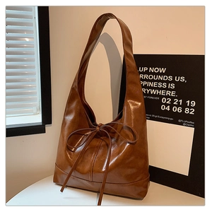 Detailed view of caramel PU leather tote bag featuring a decorative slender bow tie accent