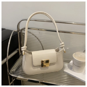 Detail of cream white baguette bag with golden metal buckle and knot strap design