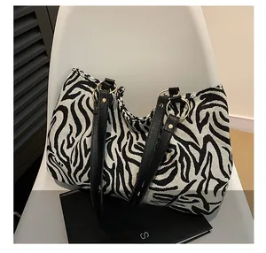 Detailed view of the large zebra print tote bag with black leather straps and gold rings