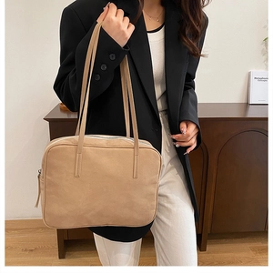 Minimalist beige tote bag in matte suede texture shown on shoulder for daily commute