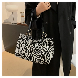 Detail of zebra pattern tote bag with premium black leather handle and golden hardware