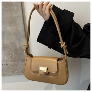 Detail of camel leather shoulder bag with golden buckle and decorative strap knots