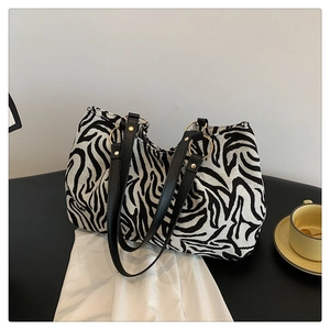 Detail view of large zebra pattern tote bag with leather handles and gold metal rings