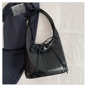 Close-up of black leather tote bag with oil-wax texture and delicate bow tie detail
