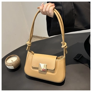 Detail of light brown leather crossbody bag featuring a golden square buckle and knot strap