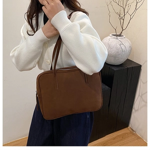 Close-up of a brown vintage square shoulder bag with a matte suede texture and slim handles