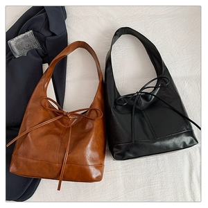 Detailed view of caramel brown and black tote bags with stylish ribbon bow accents