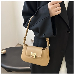 Detail of warm khaki leather shoulder bag with gold clasp and knotted strap detail
