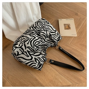 Detail of zebra print knit tote bag featuring black leather strap and gold ring buckle