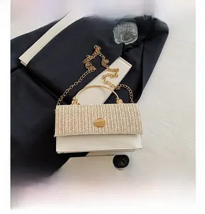 Détail du sac bandoulière en paille et cuir à côté d'un smartphone pour la taille