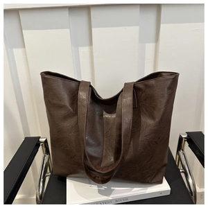 Detail of the vintage dark brown leather tote bag with a rich texture on a white chair