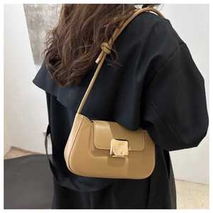 Close-up of minimalist camel leather shoulder bag featuring a square gold metal buckle