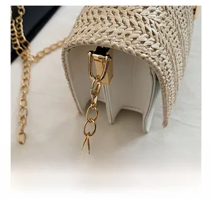 Détail de la chaîne dorée élégante et des ferrures métalliques sur le sac en paille tissée