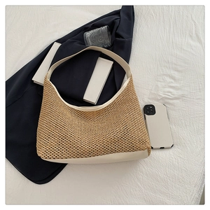 Flat lay of a woven straw hobo bag with cream leather trim on white fabric background