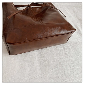 Detailed close-up of dark brown wax leather tote bag with stitch finish and drawstring