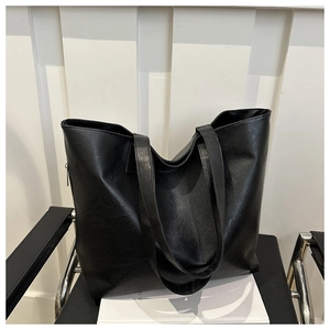 Macro shot of minimalist black PU leather tote bag showing fine texture and dual straps