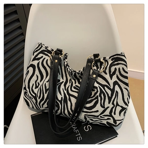 Detail of zebra print tote bag with black leather straps and gold metal hardware