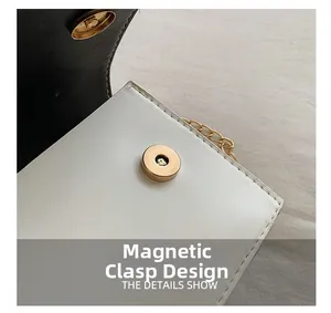 Détail d'un sac bandoulière en cuir noir et blanc avec fermeture magnétique dorée