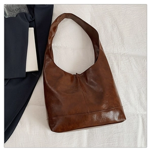 Flat lay of a large brown hobo tote bag on white texture with blue blazer detail