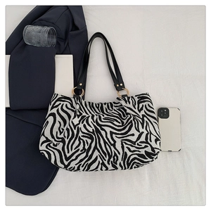 Zebra print tote bag detail with gold ring hardware on soft white fabric background