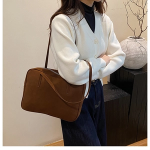 Brown textured leather shoulder bag styled with minimalist white cardigan on a model