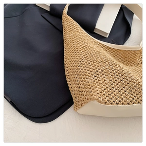 Detailed close-up of the woven texture and cream leather trim on the straw tote bag