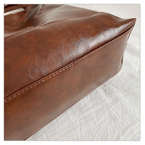 Macro shot of dark brown faux leather tote bag base with precise reinforced stitching