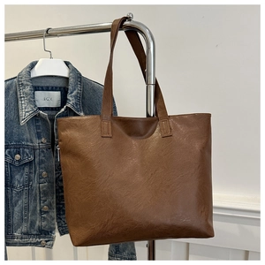 Detail shot of a brown faux leather tote bag showing textured grain and glossy finish
