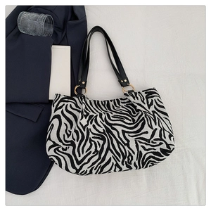 Close-up of zebra pattern canvas tote bag with black leather straps and metal rivets