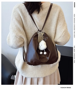 Detail of dark brown tote bag with adjustable straps and soft white cloud pendant