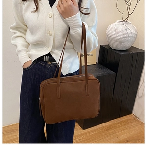 Detail view of a large brown suede shoulder bag with dual straps and silver zip closure