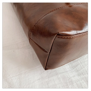 Macro detail of dark brown lychee texture leather and fine stitching on the bag base