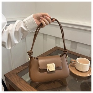 Close-up of brown leather shoulder bag with gold square buckle and knotted strap detail
