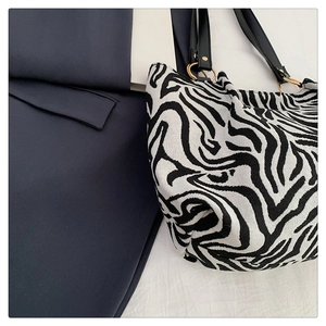 Detail of zebra pattern tote bag with gold metal ring connectors and black straps