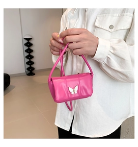 Detail of a bright pink mini crossbody bag with a white butterfly ornament on the front