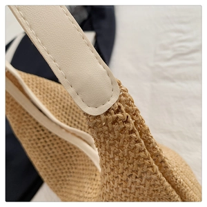Macro detail of the woven straw texture and leather strap stitching on the tote bag