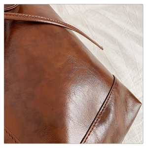 Detail of caramel brown glossy leather texture and precision stitching on shoulder bag