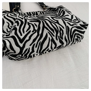 Detail of zebra print canvas tote with thick texture and golden metal ring hardware