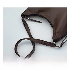 Detail of soft brown leather shoulder bag featuring silver zipper and sturdy metal rivets