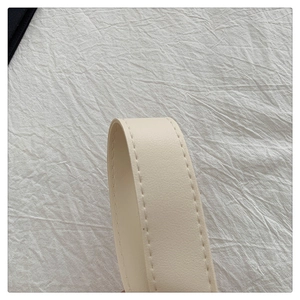 Macro detail of the cream faux leather strap with fine stitching on the woven tote bag