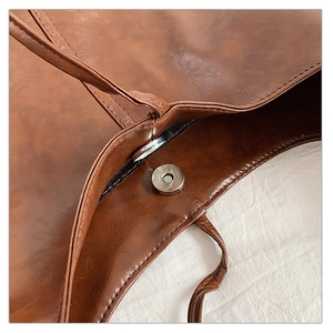 Detail of vintage brown tote bag with magnetic clasp closure and fine stitching