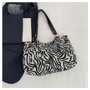 Detailed view of zebra print tote bag with black shoulder strap and gold hardware
