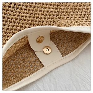 Detail of hand-woven straw tote with premium cream leather trim and magnetic gold closure