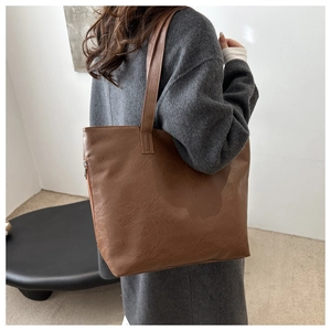 Rear view of a model wearing a large brown tote bag with smooth texture and shoulder straps