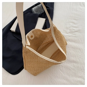 Detail view of woven straw tote bag with magnetic clasp and cream shoulder straps
