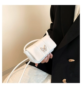 Close-up of white mini flap bag with gold butterfly clasp on a black blazer background