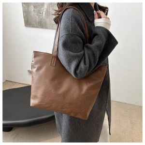 Side view of dark brown faux leather tote bag worn by a model in a minimalist studio